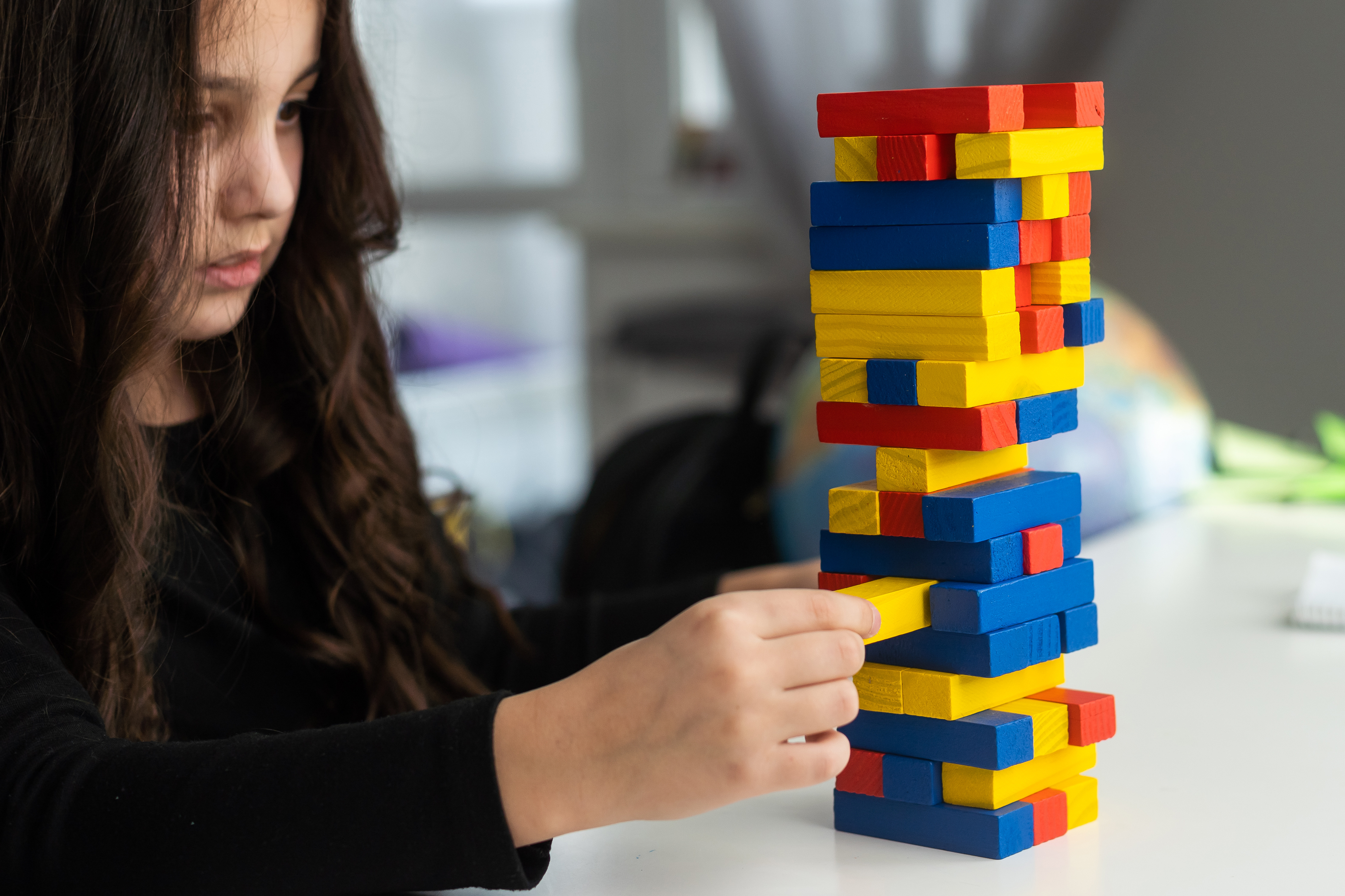 Mädchen spielt konzentriert mit Bauklötzen – therapeutische Arbeit mit Kindern